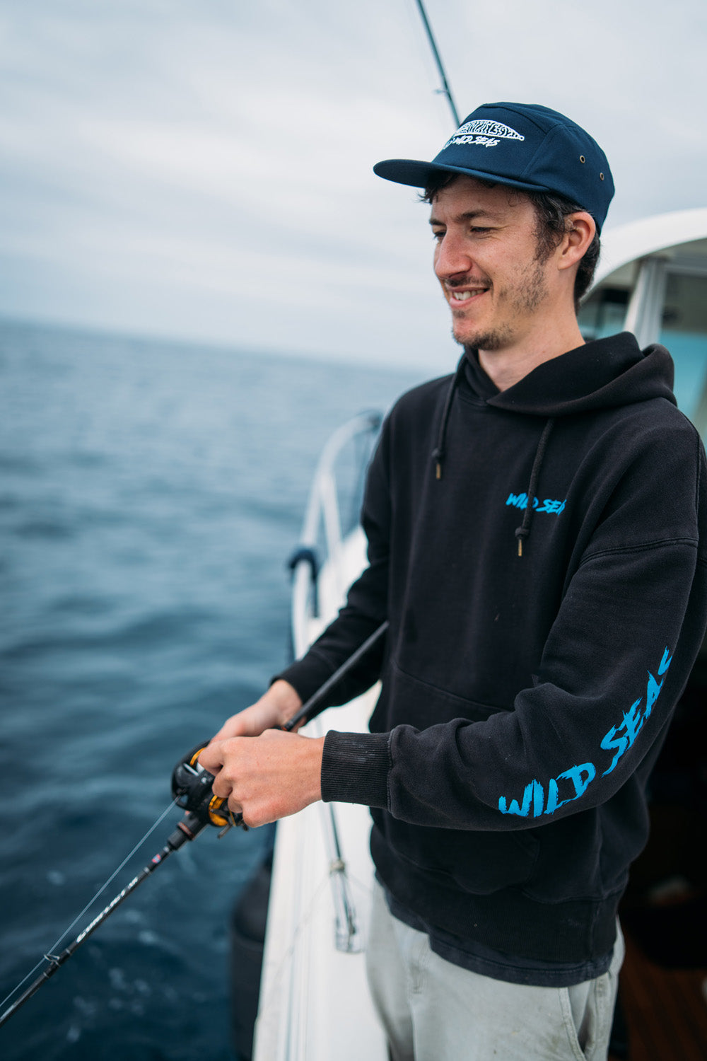 Liam wearing the Wild Seas Jigger Cap whilst fishing on a boat